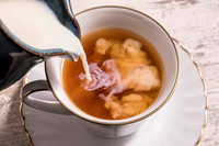 Milk being poured into a cup of hot tea